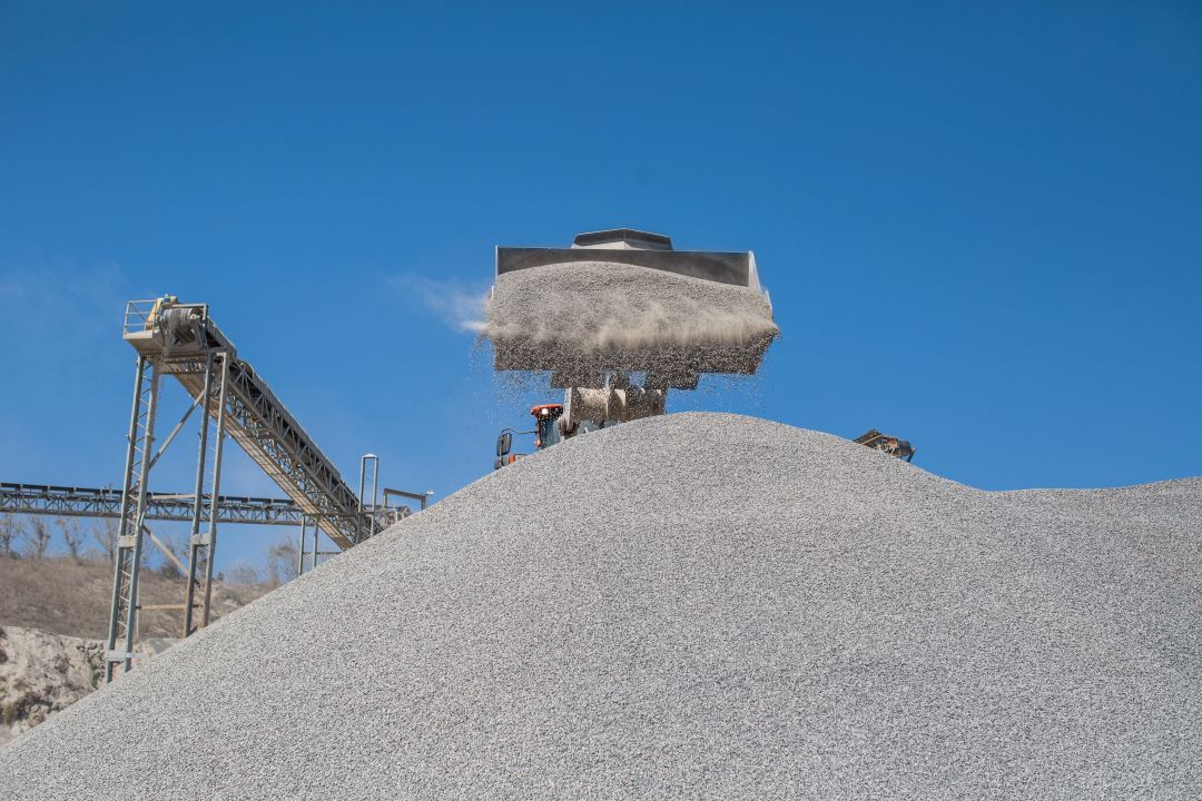 aggregate production, excavator pouring gravel to form a large pile in a mining area.
