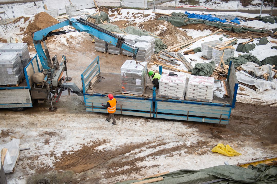 construction material management, construction site with workers, building materials, machinery and a truck