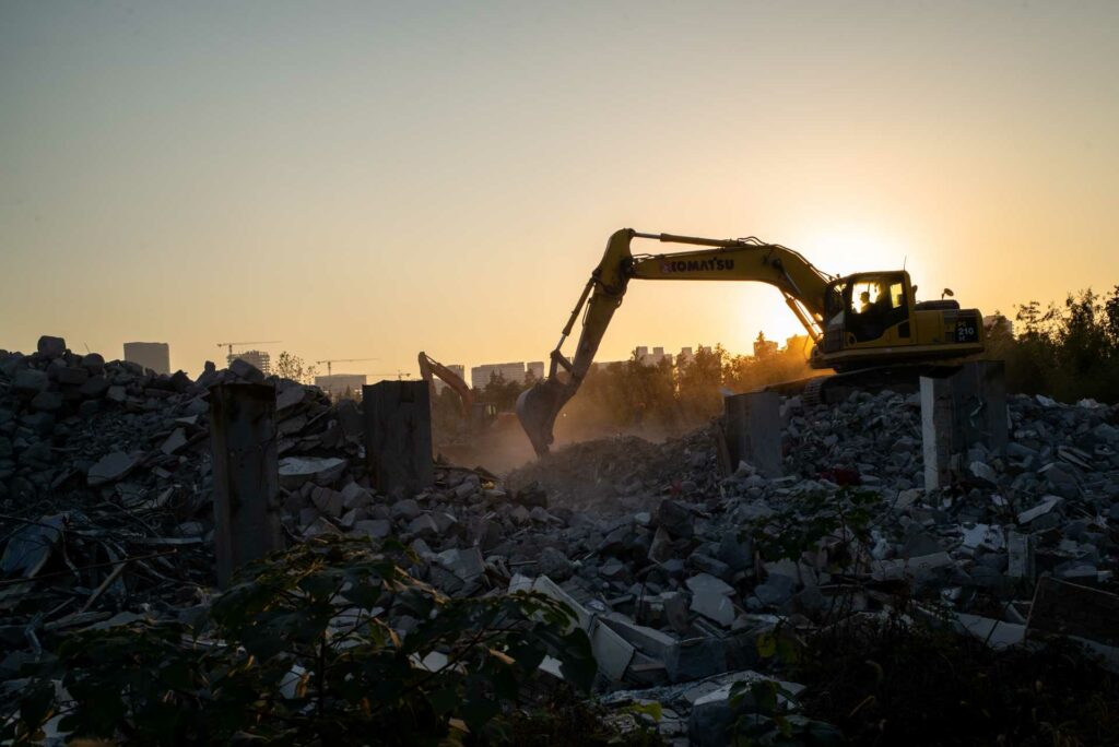 construction waste recycling process, an excavator digging in a construction waste zone.