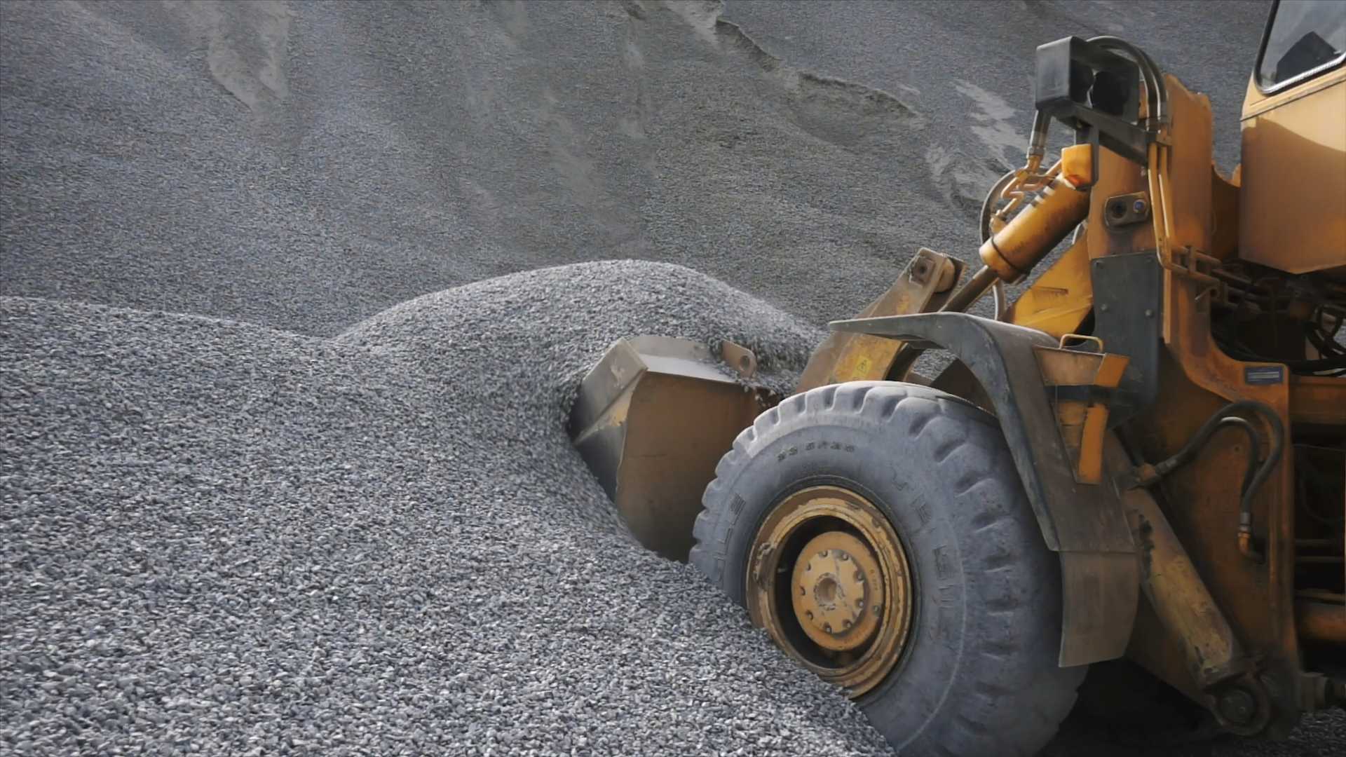 estimate aggregate tonnage, A tractor scooping gravel