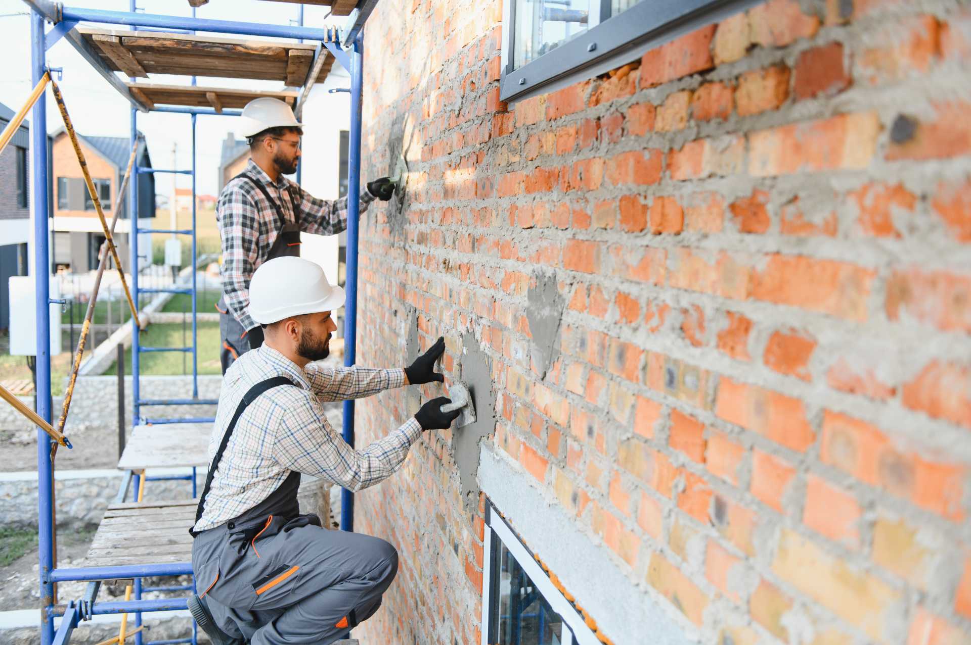 retrofitting in construction, construction workers working on a brick wall.